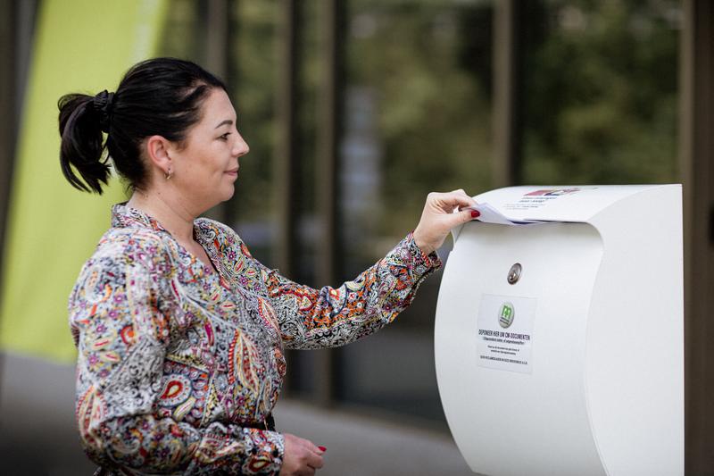 Vrouw stopt iets in de CM-brievenbus