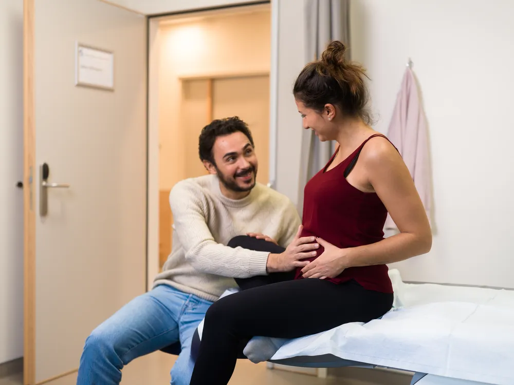 Une femme enceinte est accompagnée par son compagnon lors d'une consultation chez le gynécologue