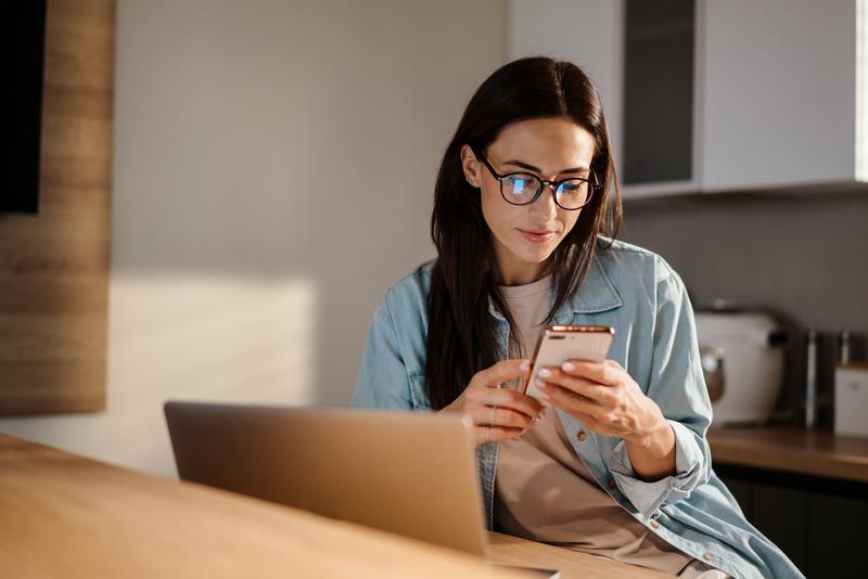 Une femme consulte son smartphone pour signaler une fraude