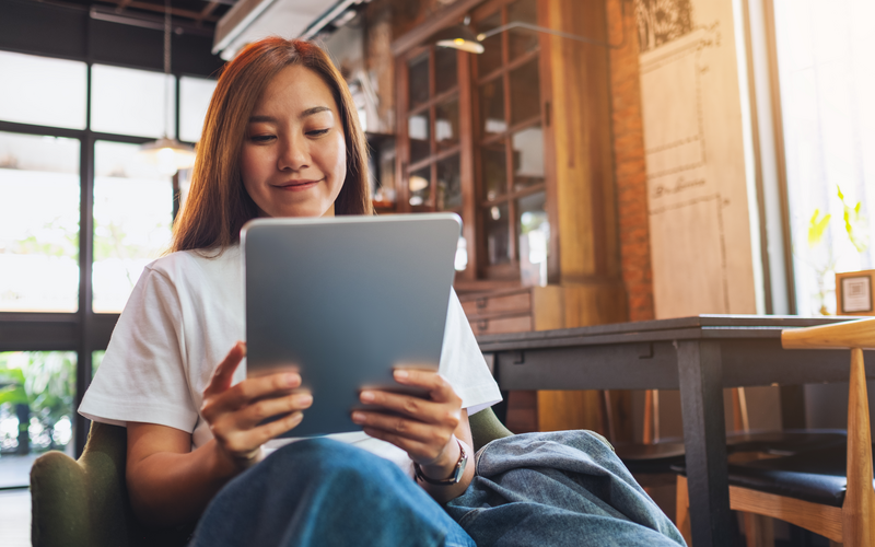 A beautiful young asian woman holding and using digital tablet in cafe
