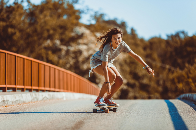Jeune femme fait du skateboard sur une route ensoleillée